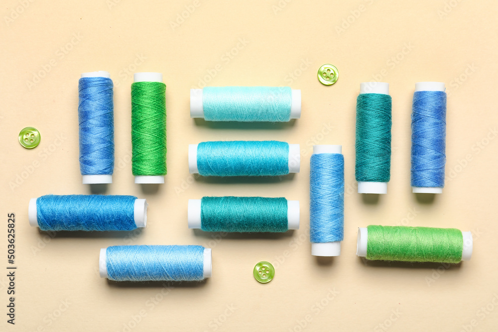Sewing threads with buttons on beige background Sewing threads with buttons on beige background