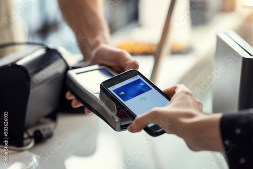 Obraz na płótnie Customer using her credit card to make payment with electronic reader in the restaurant