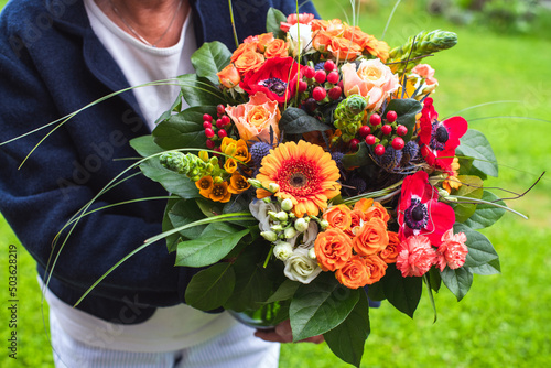 Geschenk für Muttertag, Geburtstag- ältere Dame hält wunderschönen bunten Blumenstrauss in fröhlichen Farben in den Händen photo