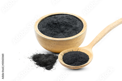 Finely crushed black charcoal is placed in a wooden cup and spoon on a completely white background.