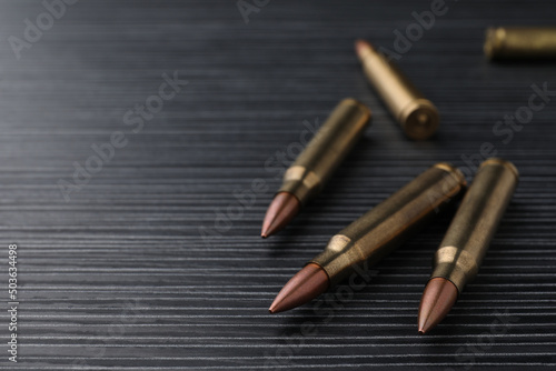 Many bullets on black wooden table, closeup. Space for text
