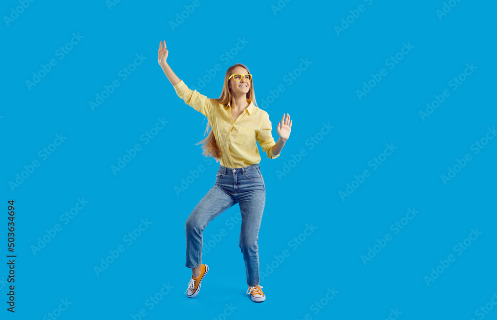 Smiling young woman isolated on blue studio background have fun dancing. Happy funny millennial teen girl feel joyful and excited make dancer moves. Party and celebration. Entertainment. Smiling young woman isolated on blue studio background have fun dancing. Happy funny millennial teen girl feel joyful and excited make dancer moves. Party and celebration. Entertainment.