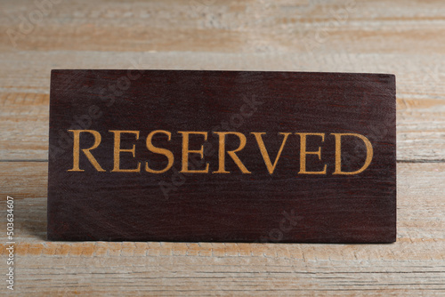 Elegant sign RESERVED on wooden surface. Table setting element