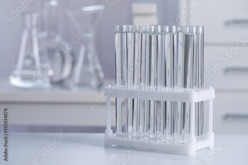 Test tubes with transparent liquid on table in laboratory. Space for text