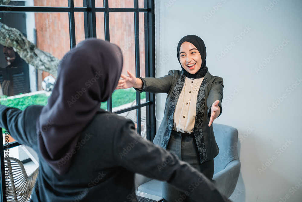 beautiful muslim worker greeting and hug her partner while meeting at the office