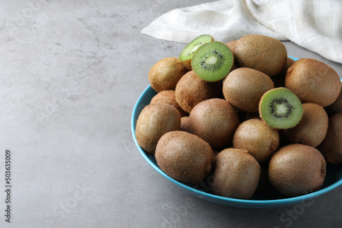Fresh ripe kiwis in bowl on light grey table  space for text