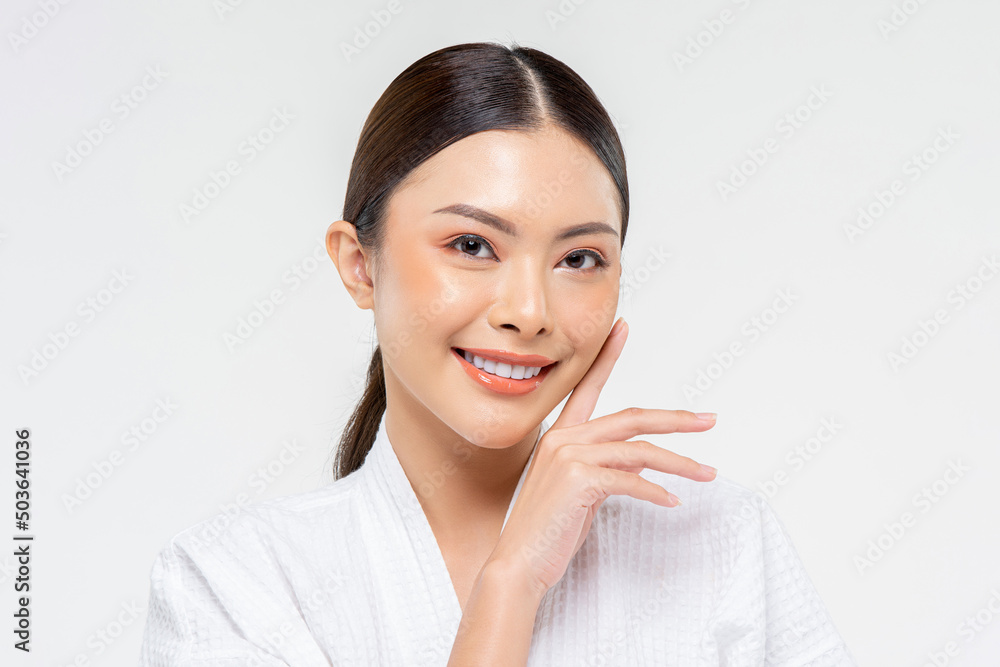 Beauty shot portrait of Asian female in bathrobe touching cheek and with smile on white isolated background in studio Beauty shot portrait of Asian female in bathrobe touching cheek and with smile on white isolated background in studio