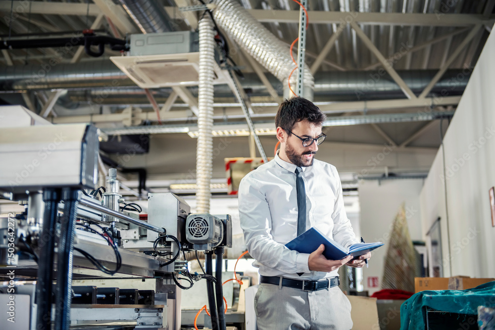 A print shop supervisor walking around facility and checking on printing machine. A print shop supervisor walking around facility and checking on printing machine.
