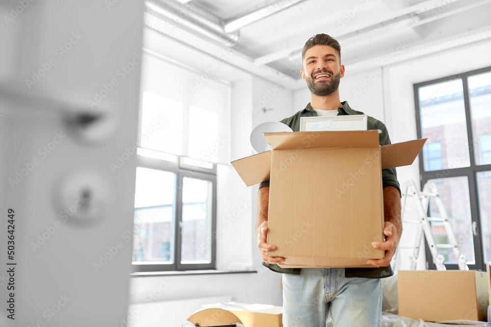 moving, people and real estate concept - happy smiling man holding box with stuff at new home moving, people and real estate concept - happy smiling man holding box with stuff at new home