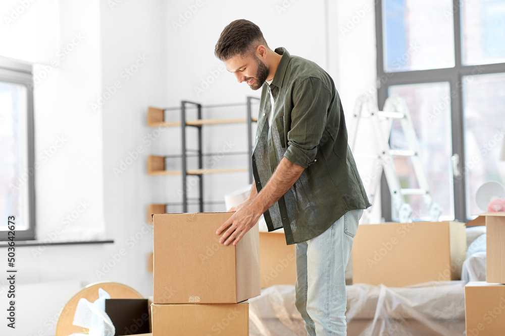 moving, people and real estate concept - happy smiling man with boxes with stuff at new home moving, people and real estate concept - happy smiling man with boxes with stuff at new home