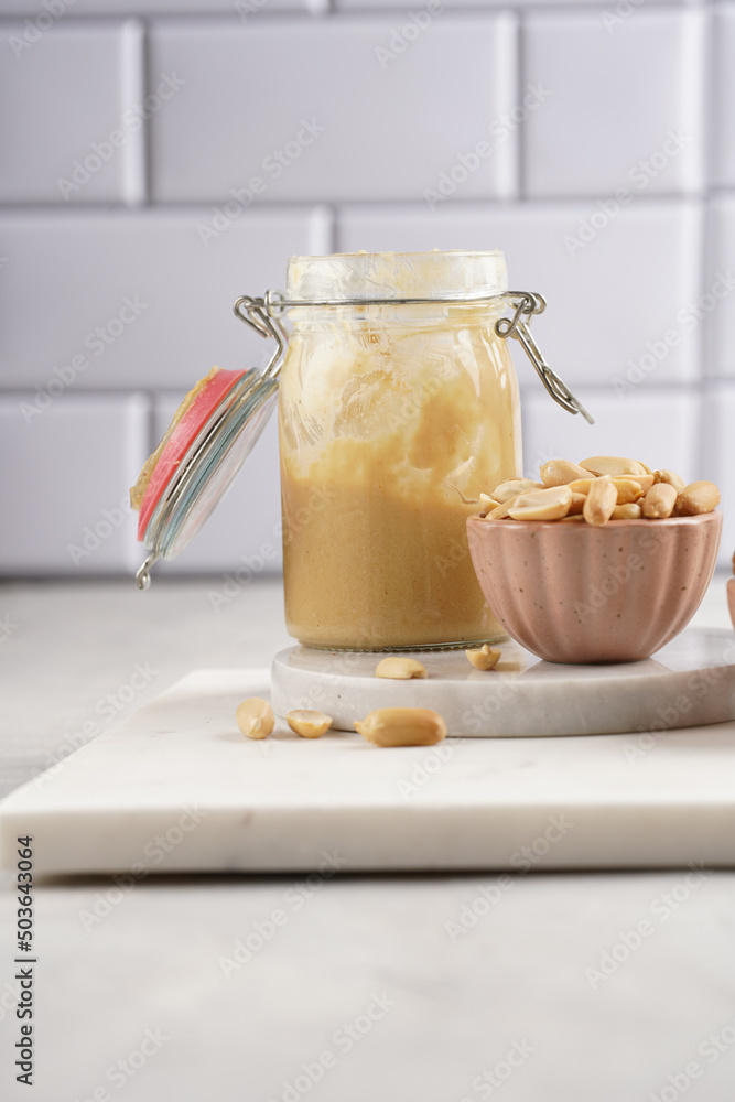 Peanuts in pink bowls, homemade peanut butter in mason jar on marble boards Peanuts in pink bowls, homemade peanut butter in mason jar on marble boards