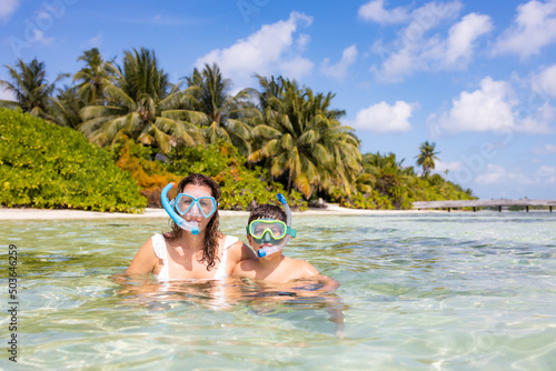 Mother and son snorkeling on a beach of the Maldive Islands