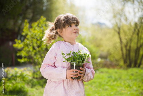 Spring awakening. Slow life. Enjoying the little things. Dreaming of spring. child with flowers in the garden. Child girl plant flowers in the garden near the houme on spring day.