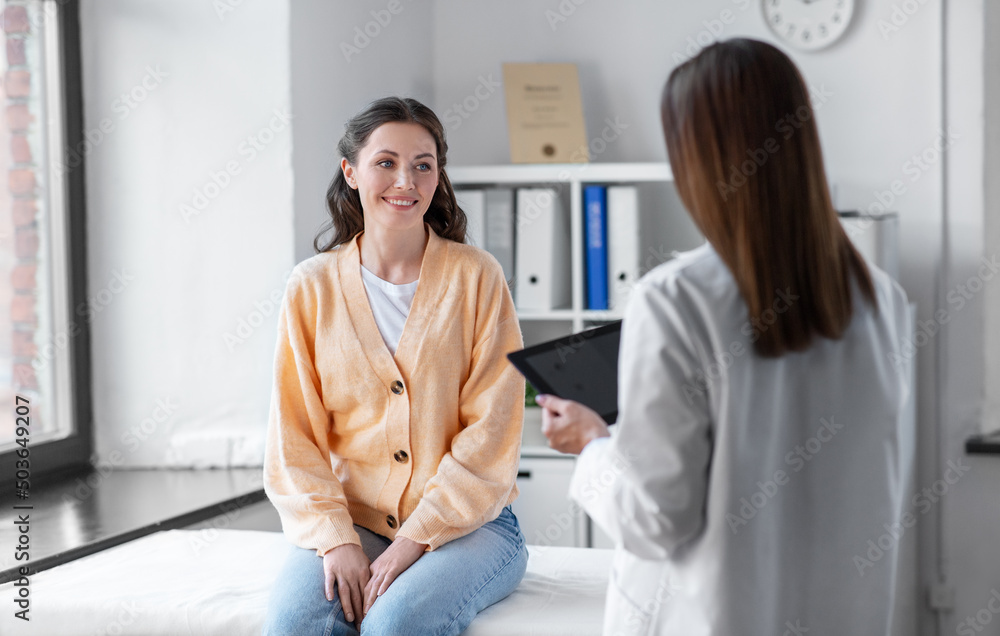 Obraz premium medicine, healthcare and people concept - female doctor with tablet pc computer talking to smiling woman patient at hospital