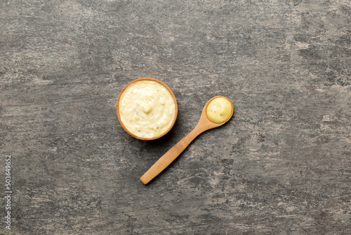 Cheese sauce in wooden bowl with spoon on cement background. Top view with copy space