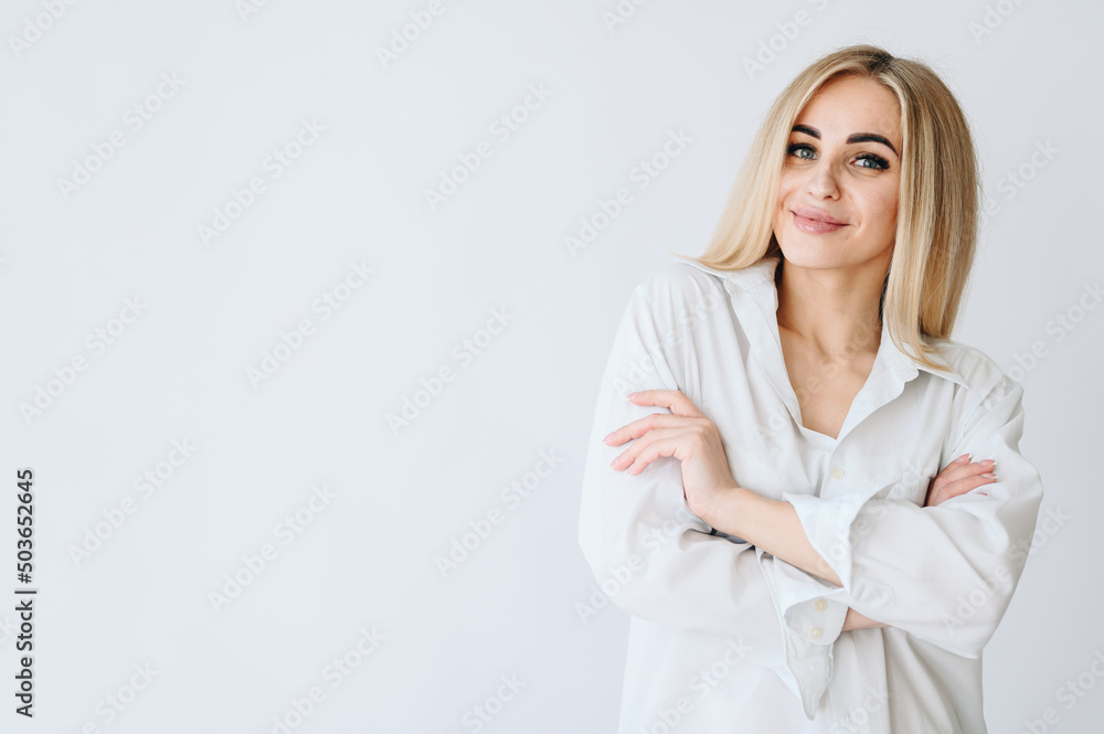 The blonde on a white background crossed her arms over her chest and smiles sweetly. The blonde on a white background crossed her arms over her chest and smiles sweetly.