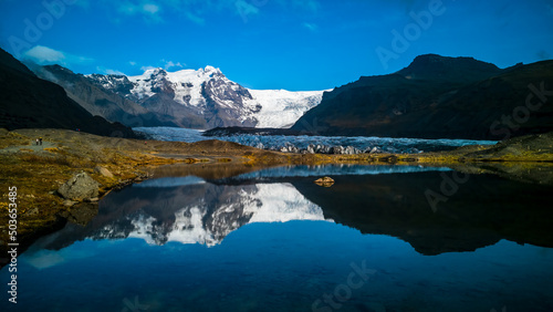 Glaciers and mountains reflected in lake with blue sky