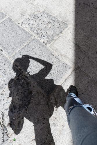 Shadow of walking photographer on the ground.