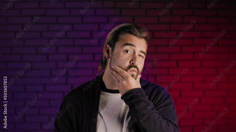 Portrait of handsome man touching his trendy beard with haircut and gesturing thumb up on camera while standing in studio. Satisfaction with appearance and narcissism concept. Portrait of handsome man touching his trendy beard with haircut and gesturing thumb up on camera while standing in studio. Satisfaction with appearance and narcissism concept.
