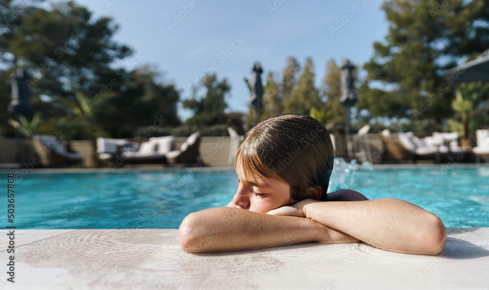 Cute 11 year old boy having a good time in the pool on a summer day
