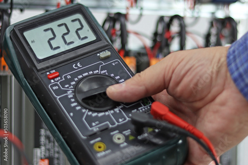 A multimeter in the hands of an engineer with the parameters of the voltage of the electric current in close-up. photo