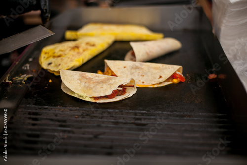 Male street vendor hands show fresh roasted meat and vegetables taco outdoors. Fresh tacos. Chef cooking mexican burito. Cook preparing delicious mexican burito at kitchen. Tasty mexican cuisine.