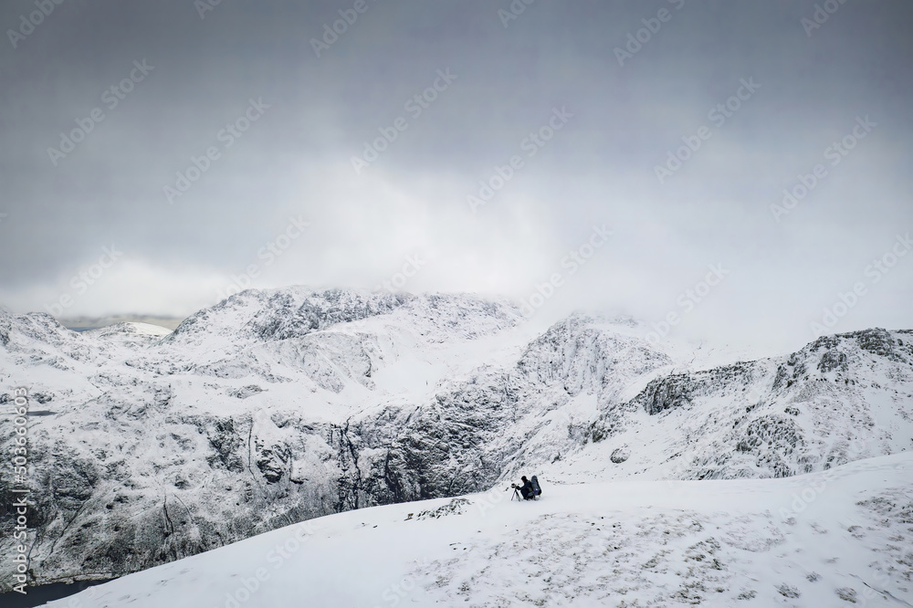 A photographer setting up high in the winter mountains of Snowdonia in North Wales