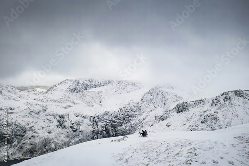 A photographer setting up high in the winter mountains of Snowdonia in North Wales