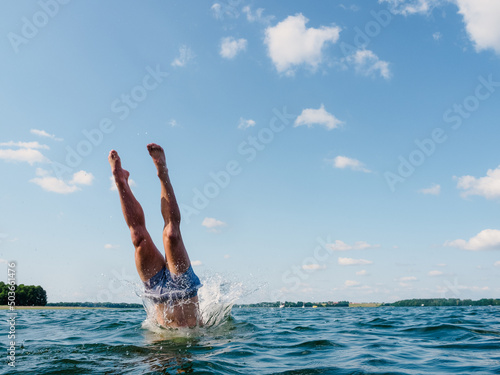 Fotografiet person diving into the water, view on human legs