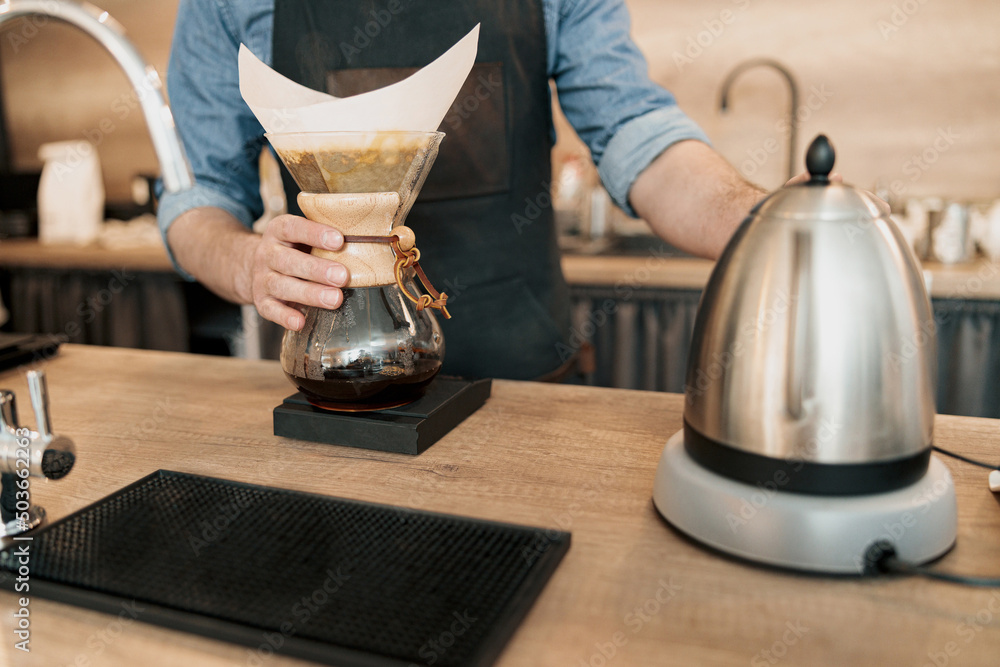 Close up of Male barista holding glass mug standing behind the counter
