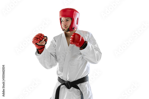 Portrait of young sportive man wearing white dobok, helmet and gloves practicing isolated over white background. Concept of sport, workout, health.