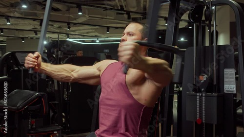 Bodybuilder performs an exercise on the chest muscles on a simulator in the gym. Sports training