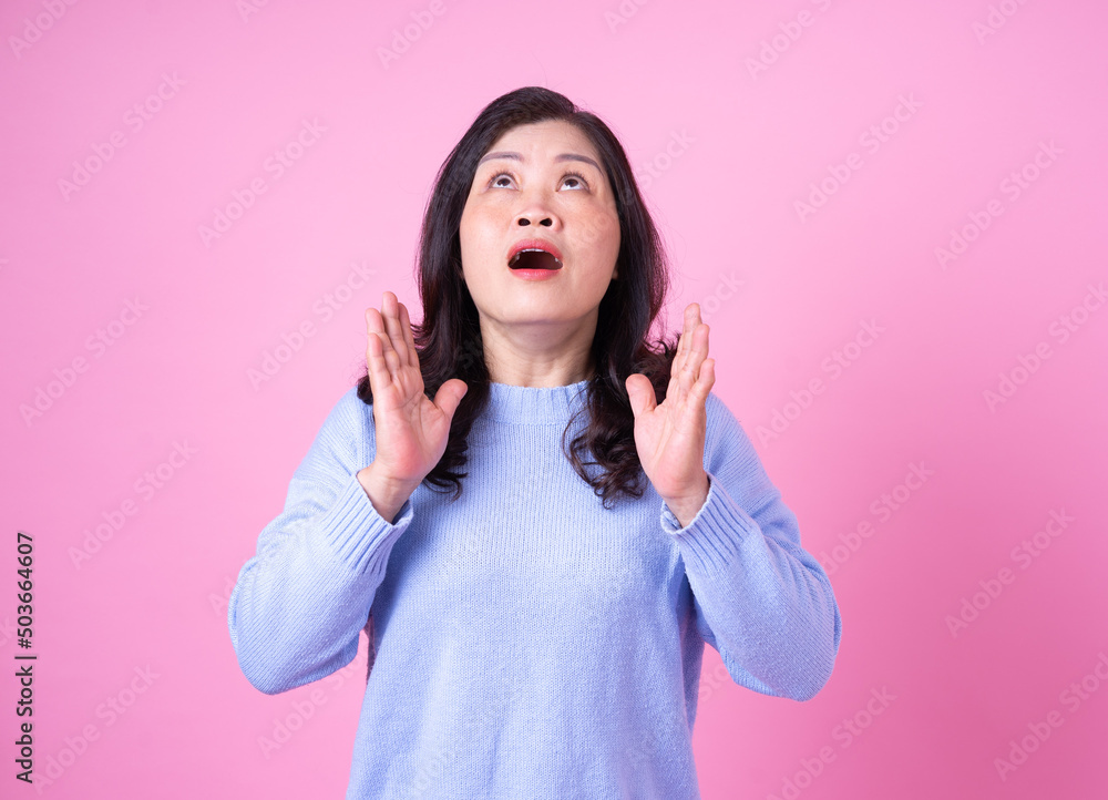 Portrait of middle aged Asian woman on pink background
Portrait of middle aged Asian woman on pink background