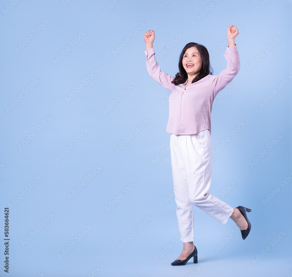 Full length image of middle aged Asian woman on blue background Full length image of middle aged Asian woman on blue background