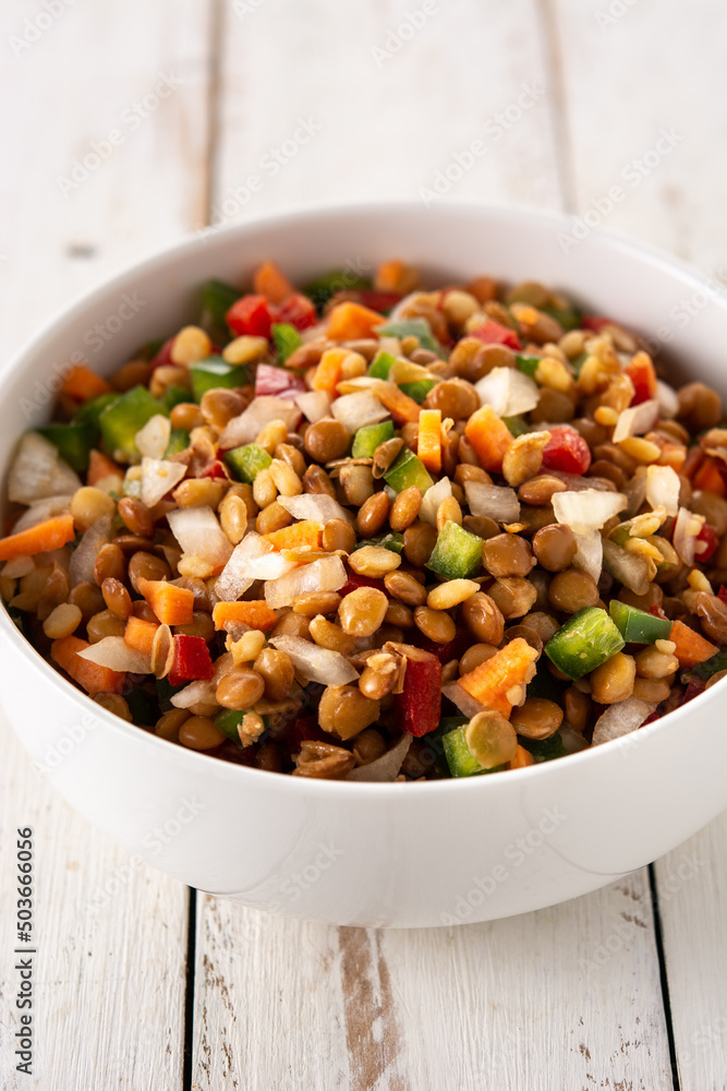 Lentil salad with peppers,onion and carrot in bowl on wooden table Lentil salad with peppers,onion and carrot in bowl on wooden table