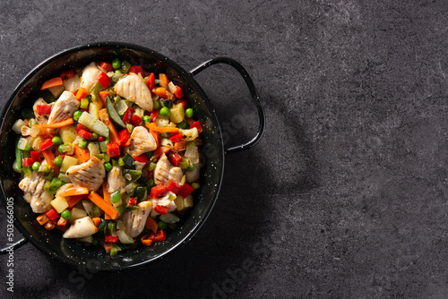 Chicken stir fry and vegetables on black stone. Top view. Copy space