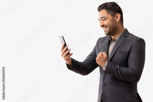 Young businessman cheering while received good news by email on mobile phone