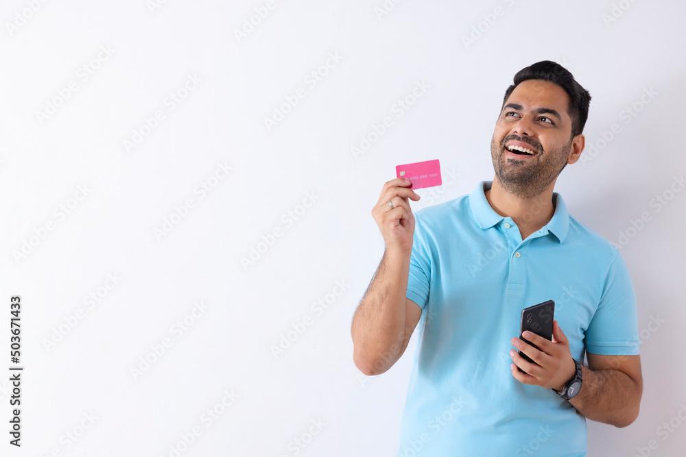 Portrait of happy young man looking elsewhere during online shopping Portrait of happy young man looking elsewhere during online shopping