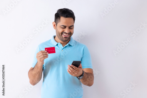 Portrait of a young man shopping online through Smartphone using credit card 