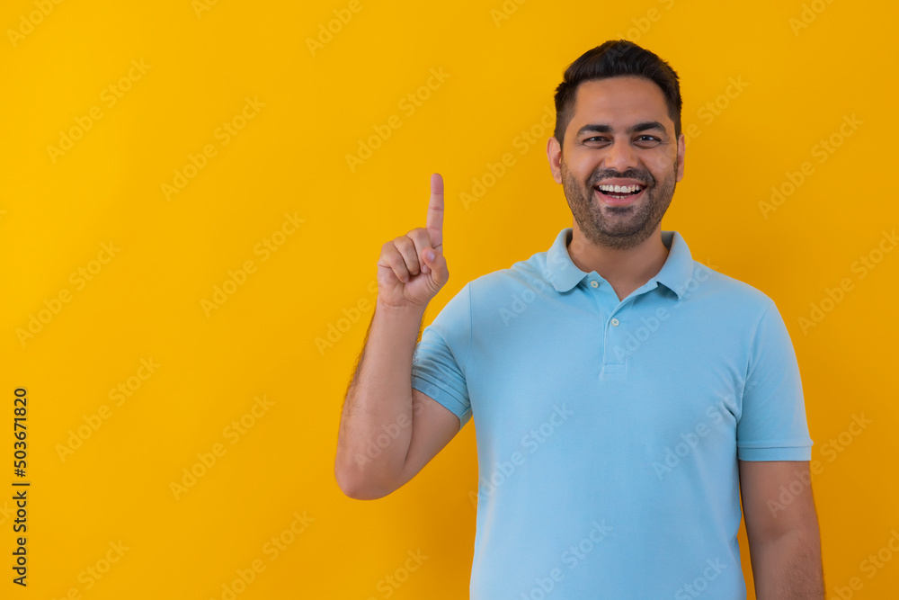 Portrait of a cheerful young man showing number with his finger against yellow background Portrait of a cheerful young man showing number with his finger against yellow background
