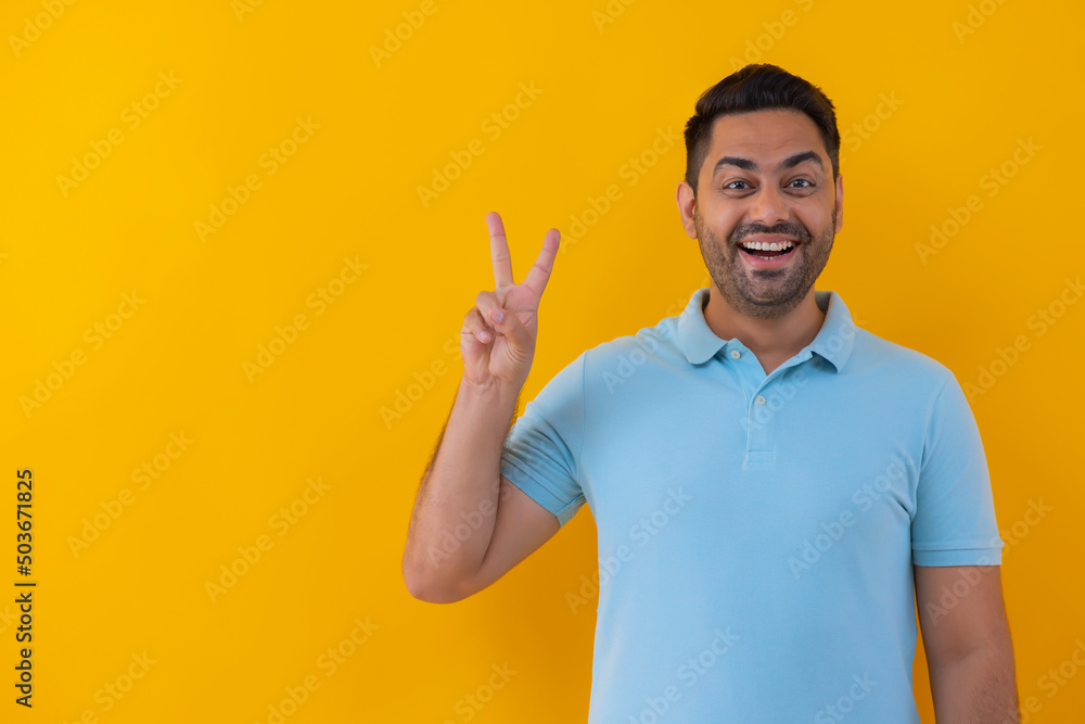 Portrait of a cheerful young man showing number with his fingers against yellow background Portrait of a cheerful young man showing number with his fingers against yellow background