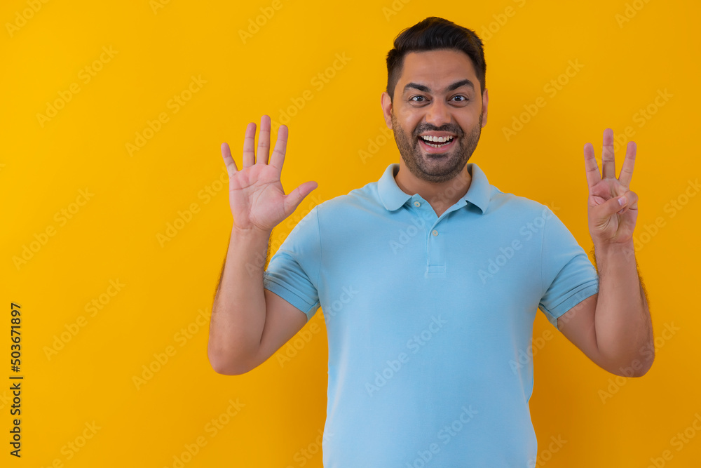 Portrait of a cheerful young man showing number with his fingers against yellow background Portrait of a cheerful young man showing number with his fingers against yellow background