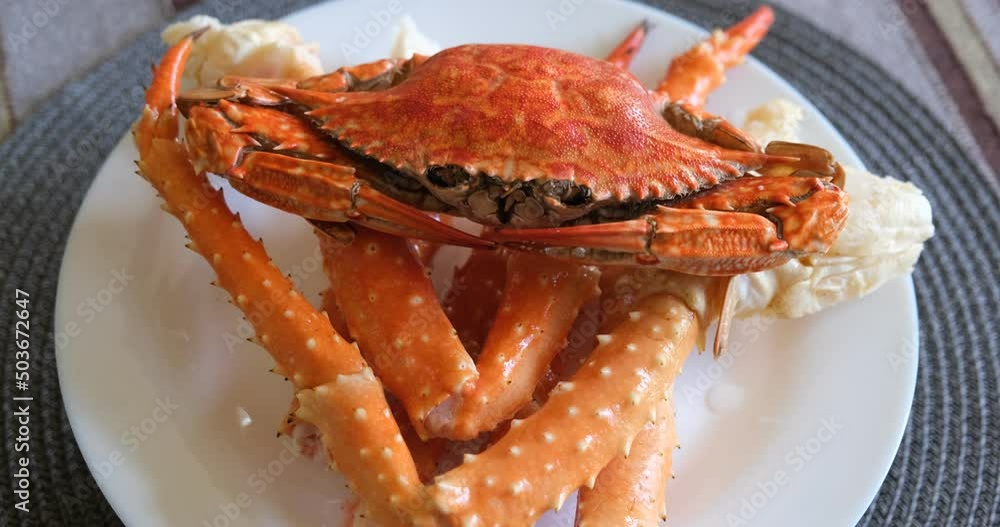 boiled crabs on a white plate. red and white crab claws and legs. floating crab lies on the legs of a king crab boiled crabs on a white plate. red and white crab claws and legs. floating crab lies on the legs of a king crab