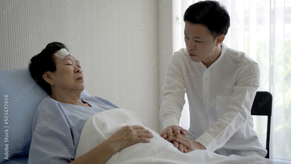 Fototapeta premium Asian family adult son worry take care of ill elderly mother admit sleeping in hospital bed