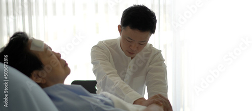 Asian family adult son worry take care of ill elderly mother admit sleeping in hospital bed