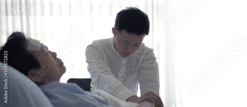 Asian family adult son worry take care of ill elderly mother admit sleeping in hospital bed