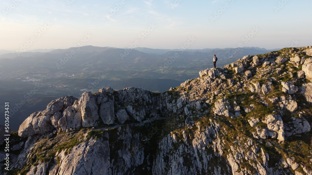 Fototapeta premium man standing on the top of a mountain at sunset in Urkiola Natural Park in the Basque Country, Spain