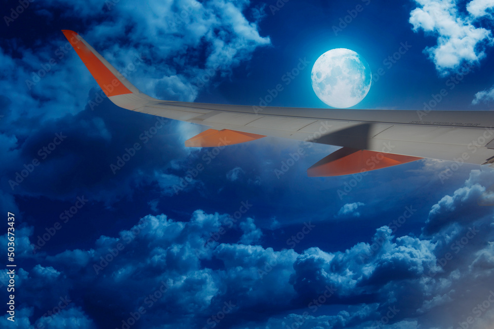 Fototapeta premium airplane wing in flight on a clear night with the moon-