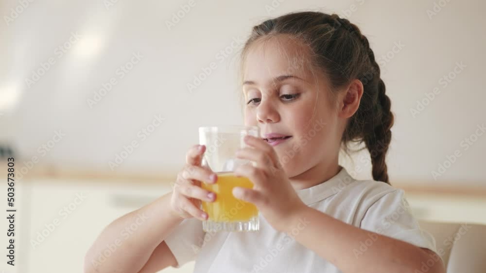 girl child drinking juice. happy family a healthy eating kid dream concept. indoors daughter girl drinking yellow juice from a glass cup in the kitchen. child drinking fruit juice girl child drinking juice. happy family a healthy eating kid dream concept. indoors daughter girl drinking yellow juice from a glass cup in the kitchen. child drinking fruit juice