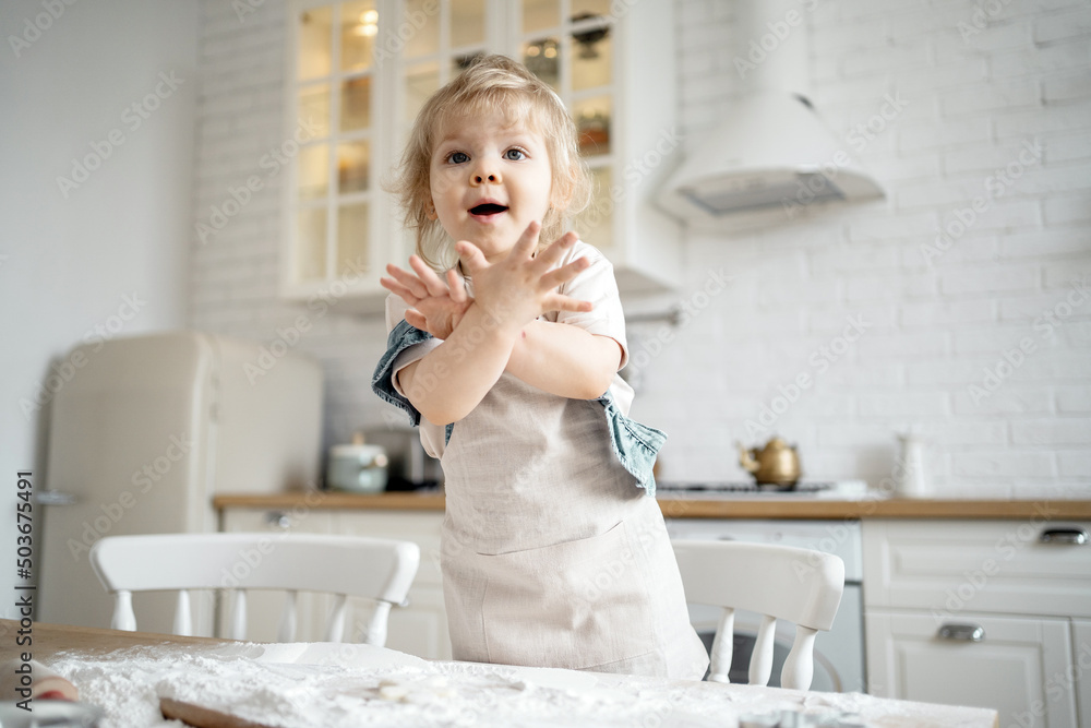 A little girl in the kitchen is playing, preparing cookies for the cook.
